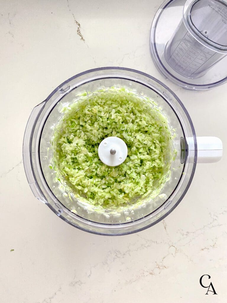 Processed broccoli and carrots in a food processor.