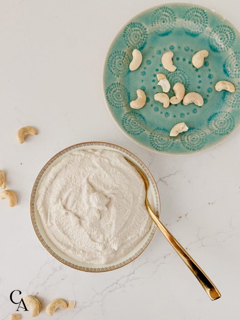 Turquoise plate with nuts and a bowl of cashew cream.