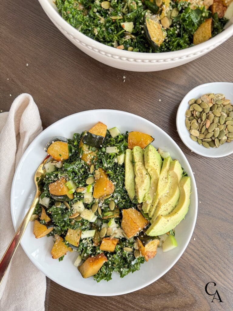 A bowl of kale salad and acorn squash with pumpkin seeds.