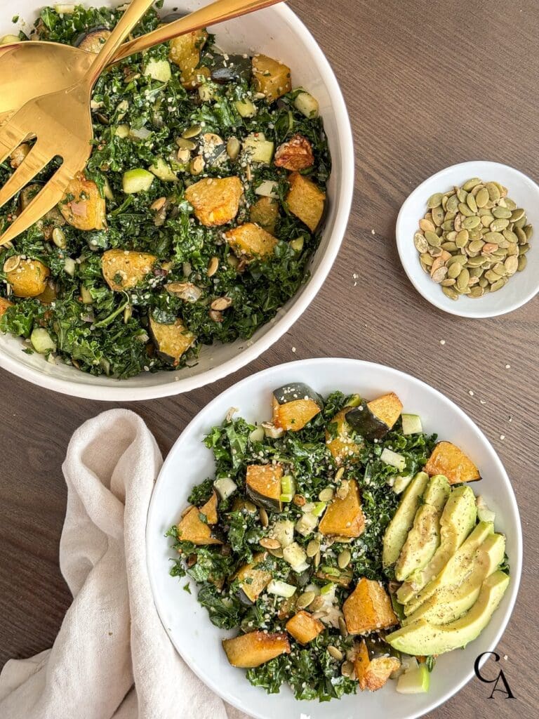 Two bowls of kale apple salad on a wood table.