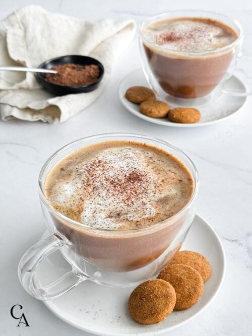 Two lattes with cookies and a napkin.