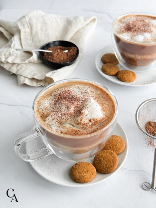 Two tiramisu lattes in glass mugs dusted with cacao powder.