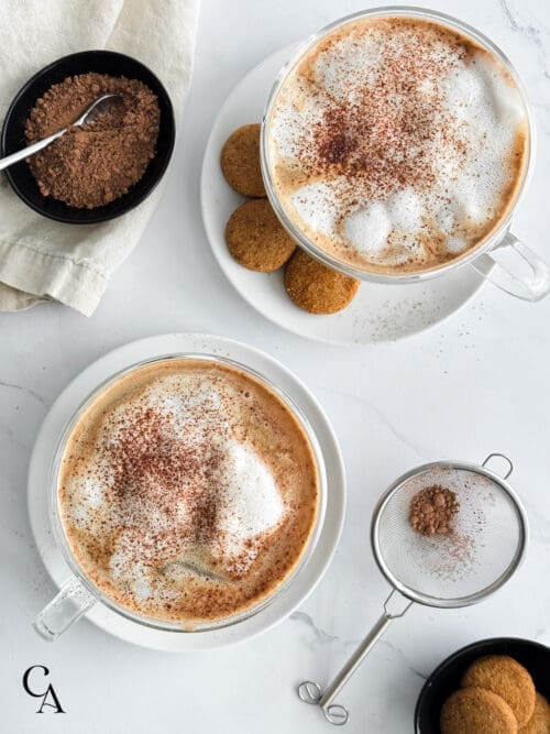 Two tiramisu lattes in tall glass mugs.