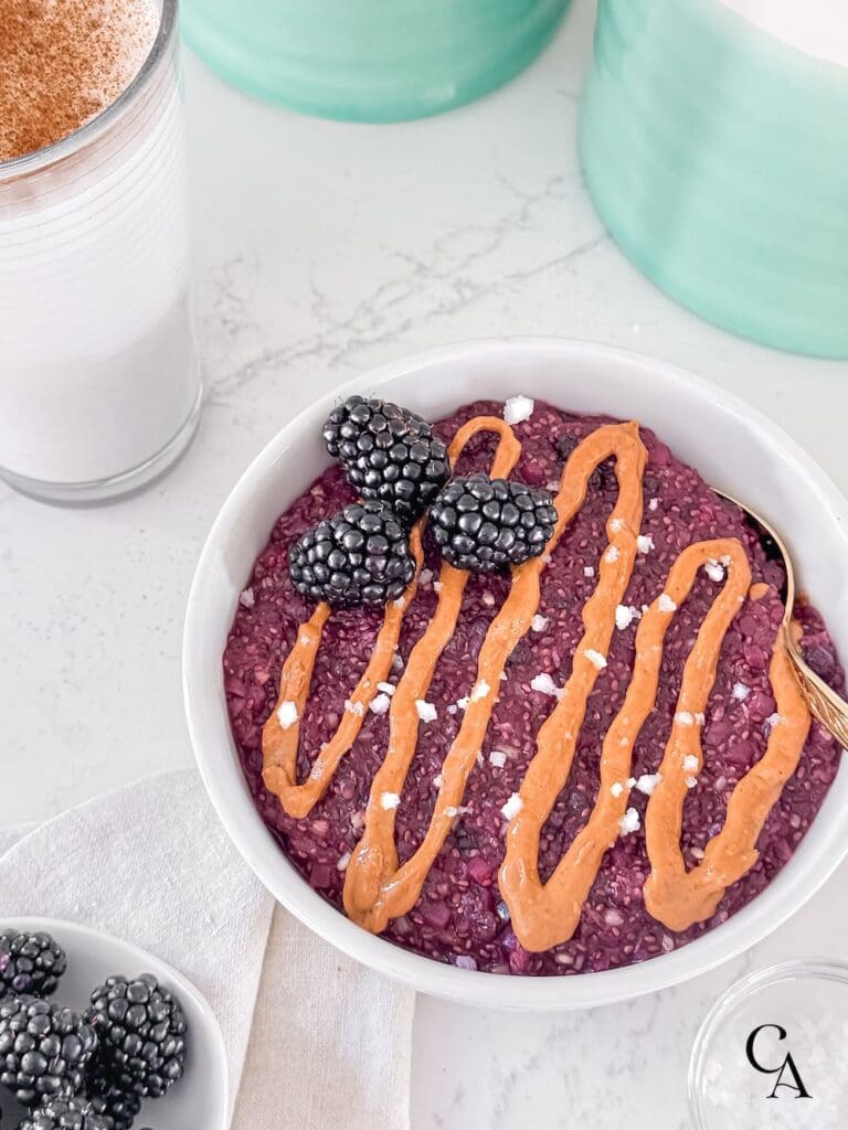 A bowl of oatmeal with blackberries and a glass of milk.