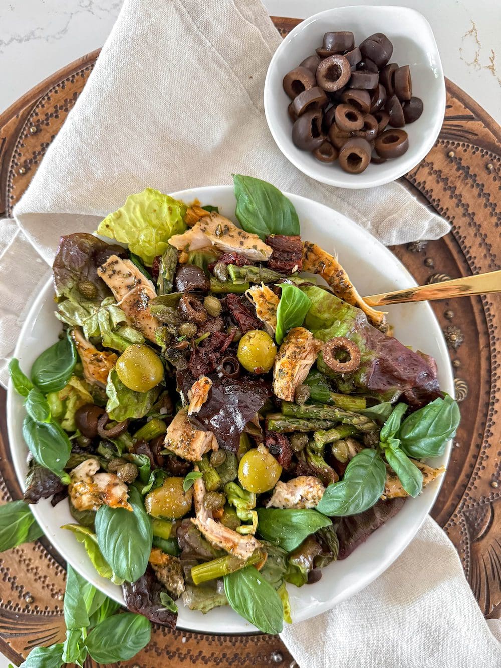 A Mediterranean salad next to a bowl of black olives.