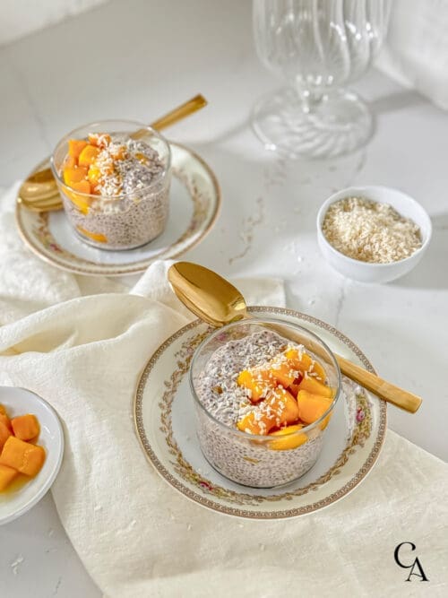 Mango chia seed pudding in glass bowls with gold spoons.