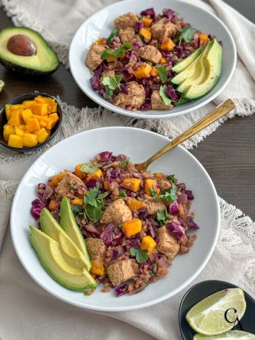 Two bowls with cauliflower rice, chicken and mango coleslaw.