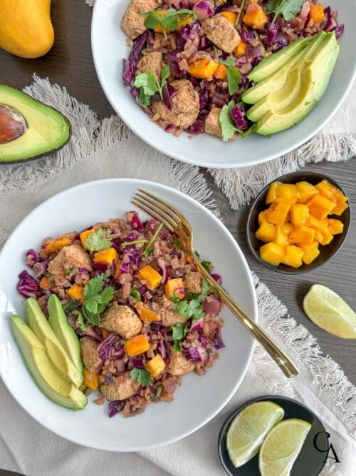 A bowl of food with fruit and avocado slices.
