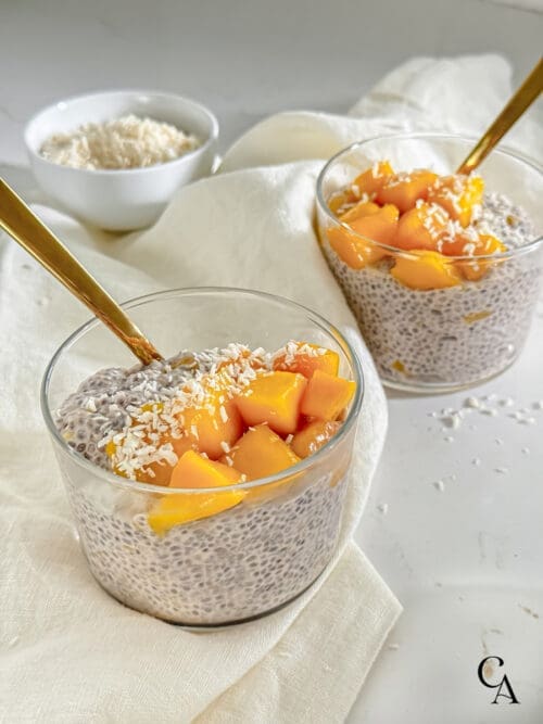 Two bowls of chia pudding with mango pieces.