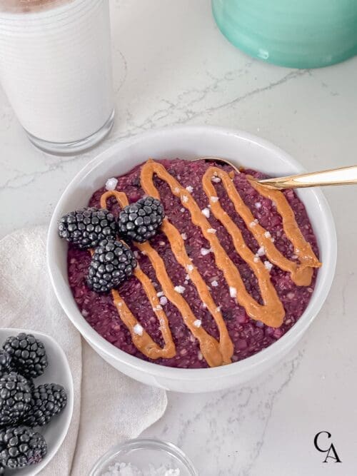 A bowl of oatmeal with cauliflower rice, berries, and peanut butter.