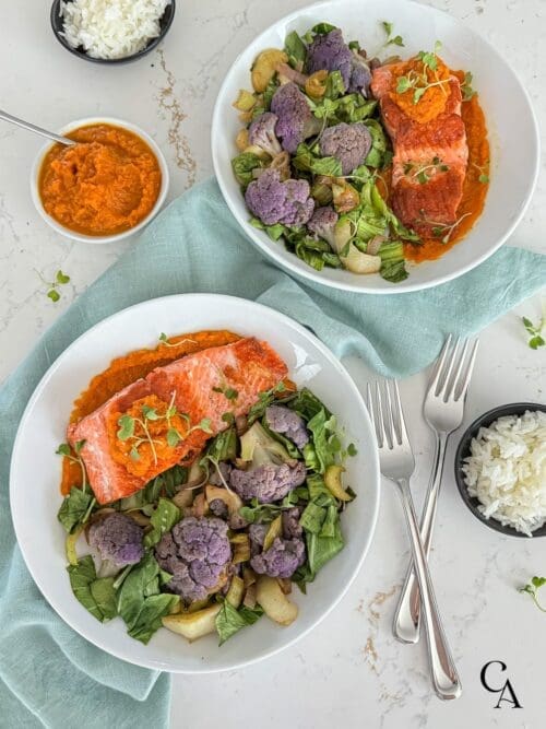 Two bowls of purple cauliflower with a brown sauce, carrot purée and white rice on the side.