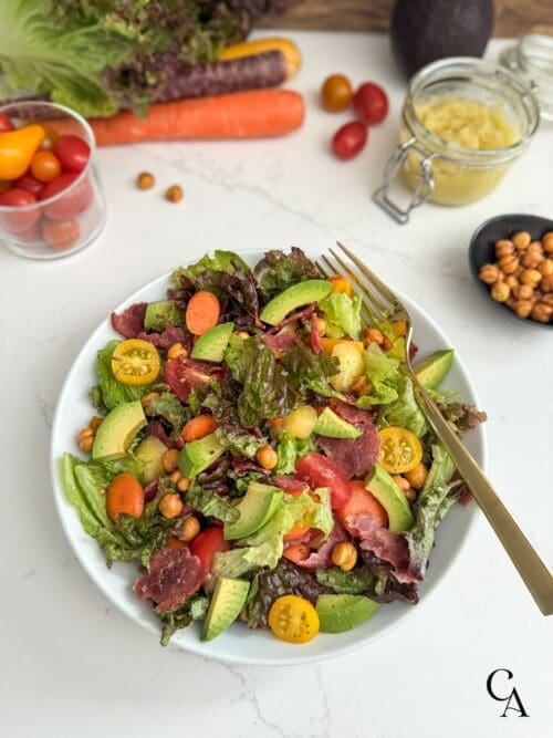 A bowl of BLT salad with avocado and carrots.