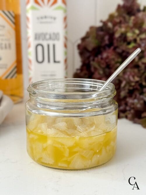 A jar of chunky sweet onion dressing with bottles of oil and vinegar and a head of lettuce.