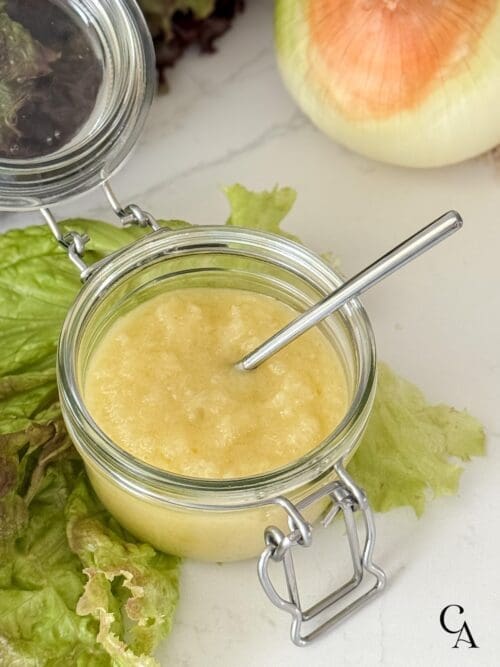 A jar of creamy sweet onion vinaigrette with a spoon.