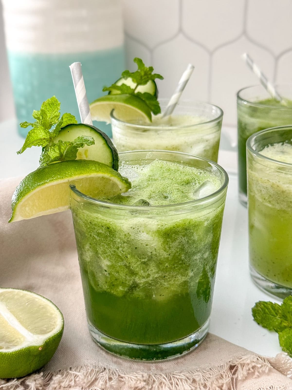 A tray of mojito mocktail with lime and cucumber garnish.