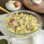 A bowl of chunky potato salad with eggs and celery leaves.