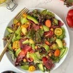 A bowl of salad with turkey bacon, lettuce, and tomato.