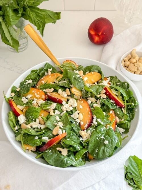 A spinach salad with nectarines and nuts.