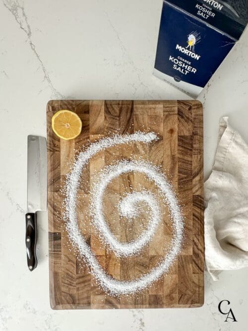 A wooden cutting board with kosher salt.