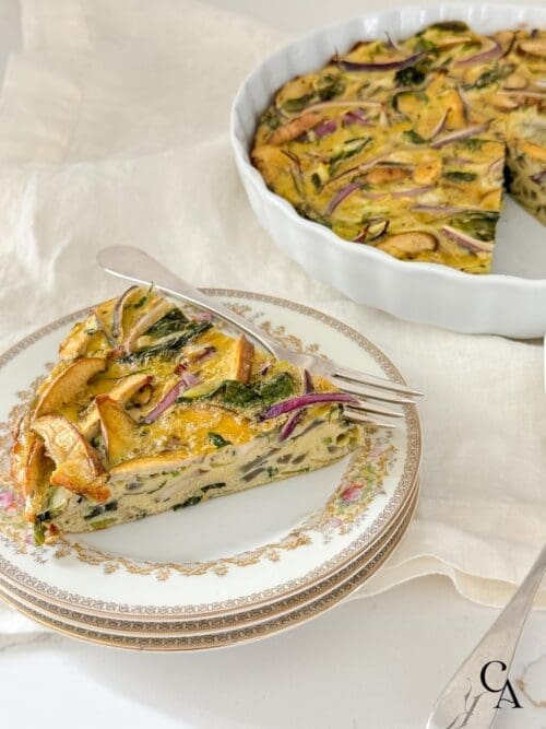 A slice of zucchini frittata on a china plate with a silver fork.