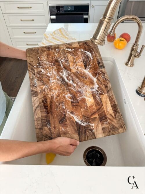 A woman holding a cutting board over the kitchen sink.