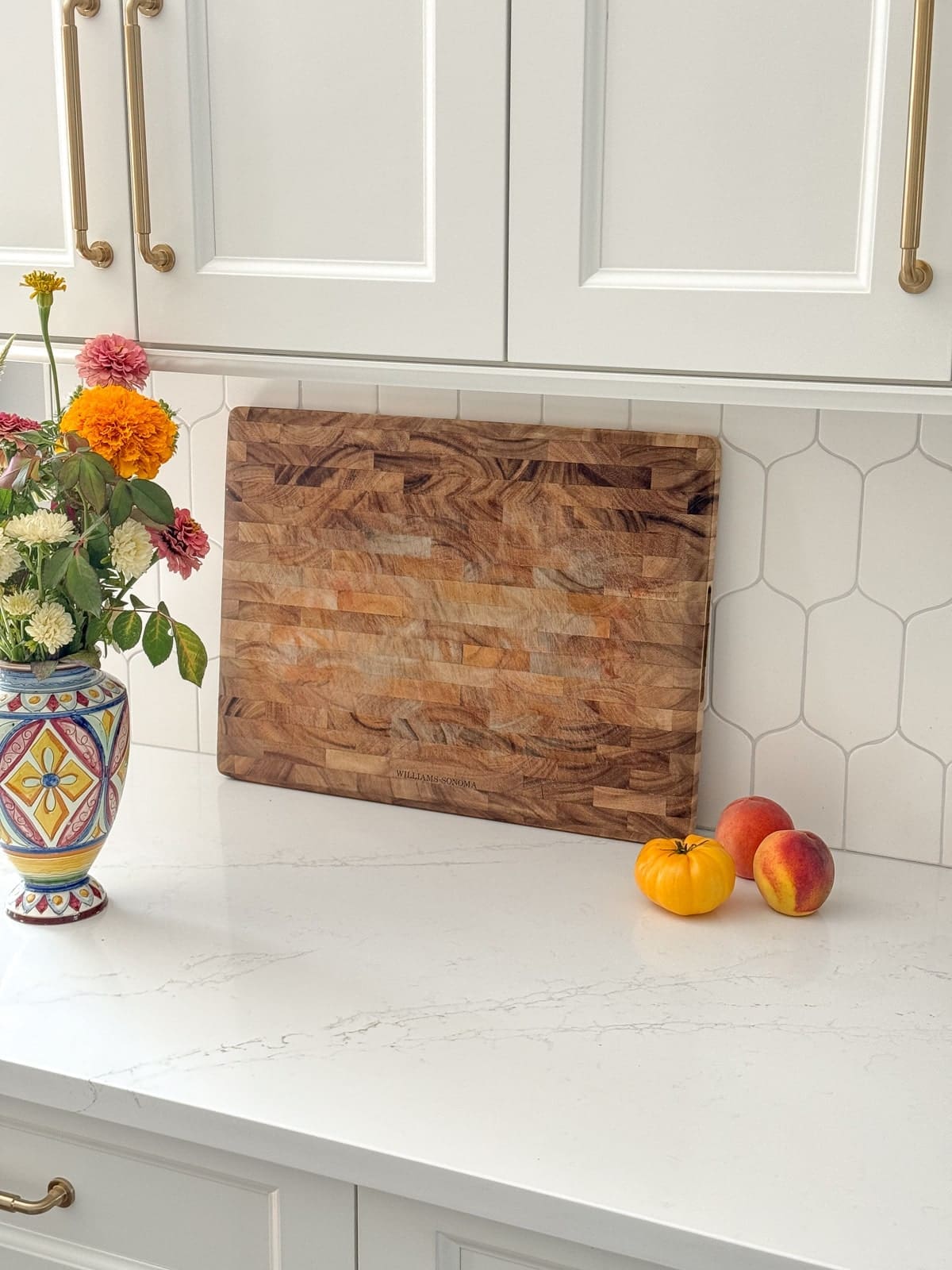 A wooden cutting board leaning against a white tile backsplash.