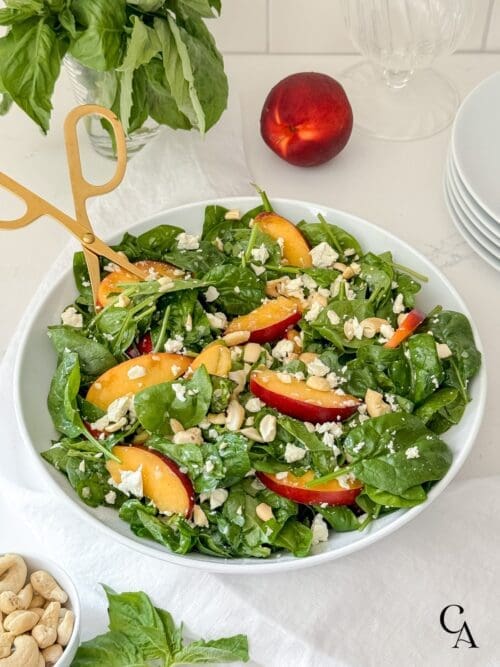 A spinach and nectarine salad with cashews and feta cheese crumbles.