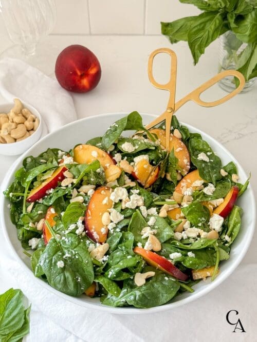 A nectarine salad with baby spinach and chopped cashews.