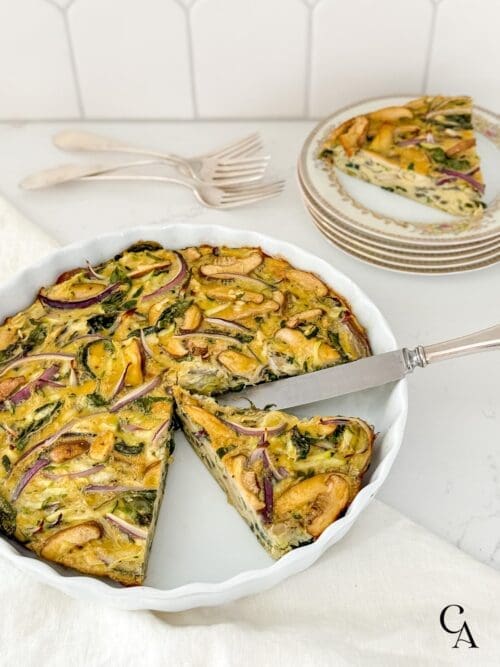 A sliced zucchini frittata with plates and utensils.