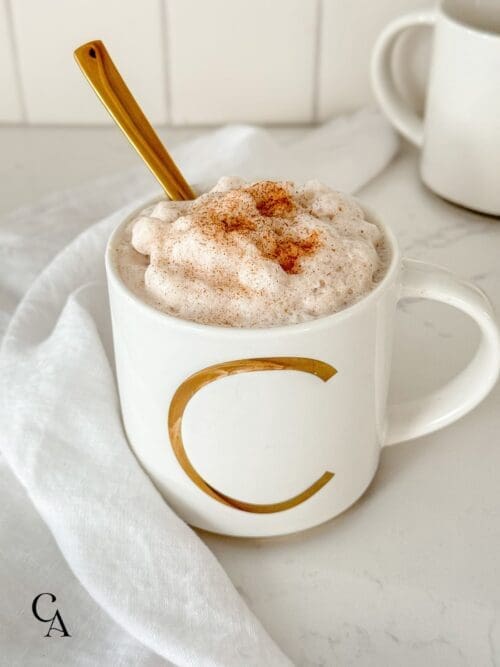 A cinnamon cacao latte with foam and a gold spoon.