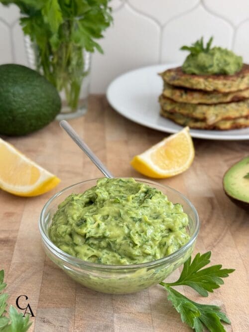 A bowl of avocado gremolata with sliced lemons.