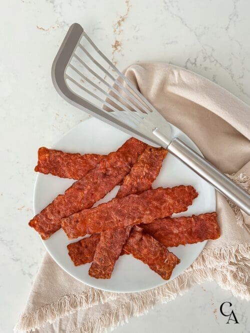 A plate of oven-baked turkey bacon next to a linen napkin.