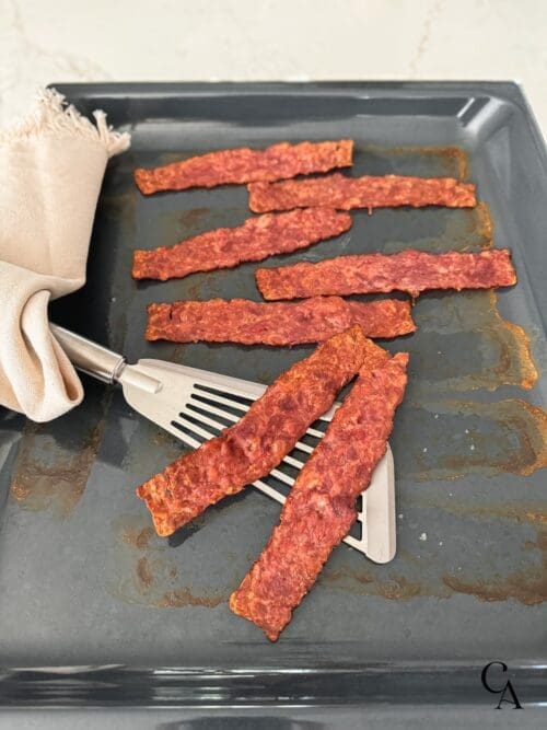 A pan of cooked turkey bacon and a spatula.