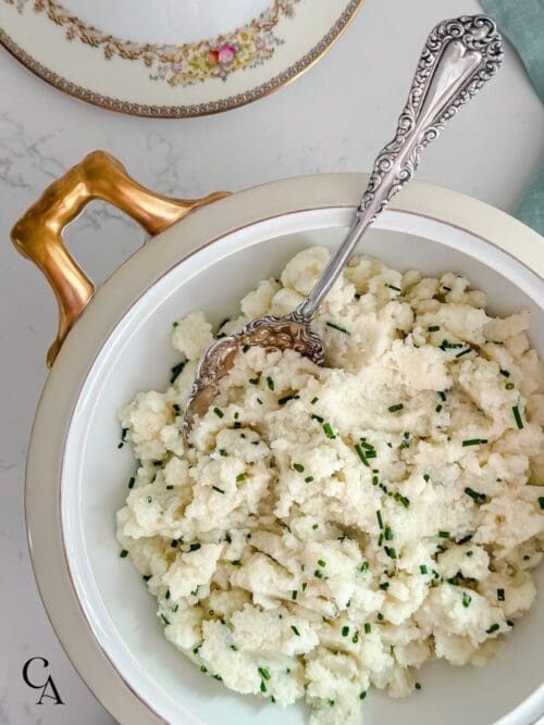 Cauliflower mash with chives and a silver spoon.