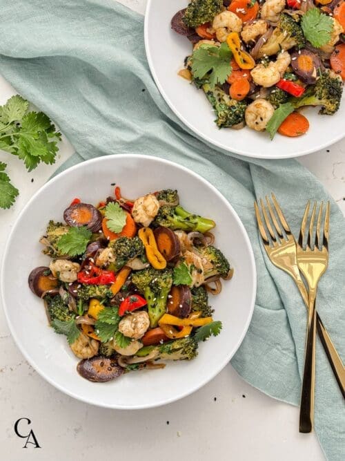 Bowls of shrimp stir-fry with cilantro and sesame seed garnish.