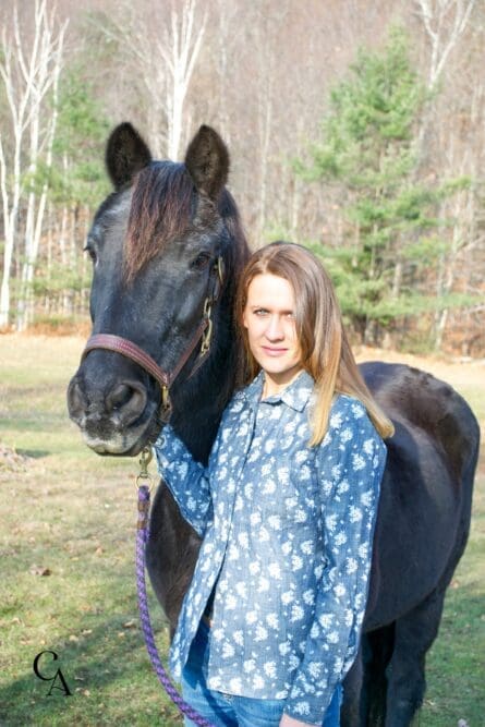 A young woman standing with a Morgan mare.