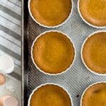 Individual pumpkin custard cups on a rimmed baking sheet.