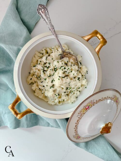 A china bowl of mashed cauliflower with a blue napkin.