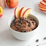 A bowl of chocolate hummus with apple slices.