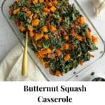 A cooked casserole with butternut squash, kale, and bacon on a stone countertop.