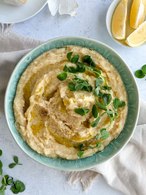 A bowl of celery root purée with pea shoots.