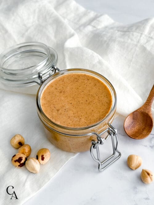 A jar of creamy hazelnut butter on a white linen napkin.