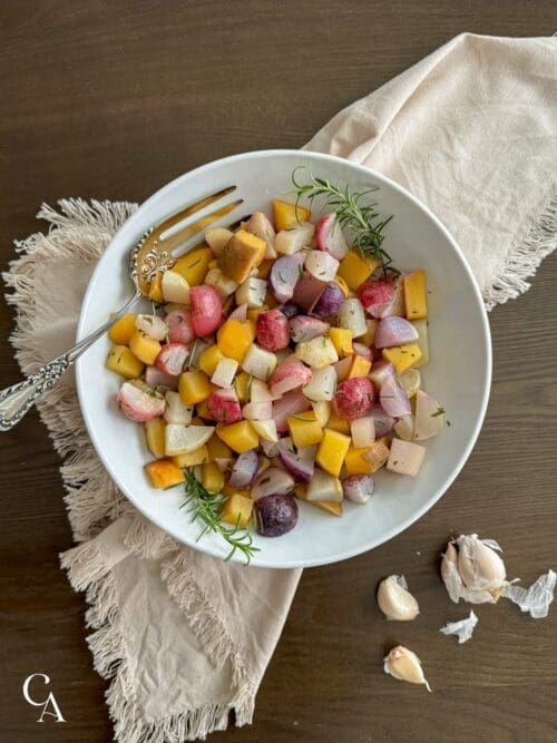 A bowl of roasted veggies with rosemary.